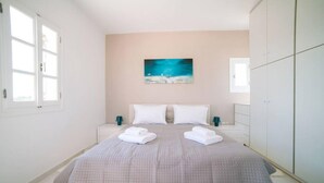 Un dormitorio con una cama, dos mesitas de noche, un cuadro en la pared y un armario.
