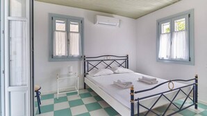 Una stanza con un letto, una finestra, un condizionatore e un pavimento a scacchi.