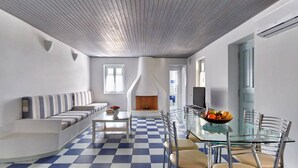 Moderni olohuone, jossa on ruutukuviollinen lattia, lasinen ruokapöytä ja seinään upotettu takka.