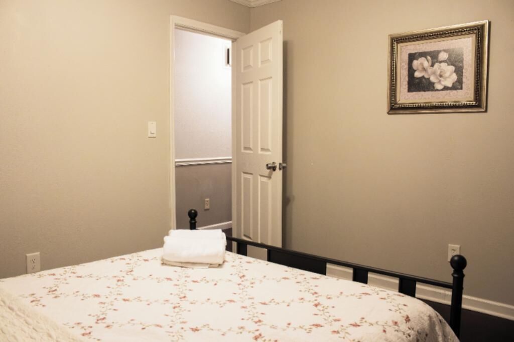 A bedroom with a bed, a door, and a framed picture on the wall.