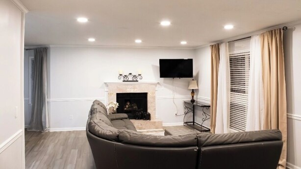 Una sala de estar con chimenea, un sofá y un televisor montado en la pared.