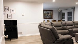 Una sala de estar con un sofá modular, un mueble de entretenimiento negro y obras de arte enmarcadas en la pared.