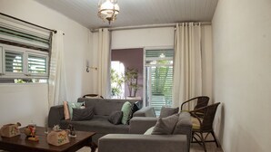 Una sala de estar con un sofá gris, dos sillones, una mesa de centro de madera y una araña.