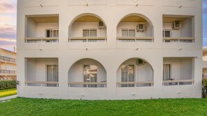A multi-story building with balconies and arched windows, surrounded by green grass. - Lefteris Insta-worthy Studio with Balcony (Ialisos)