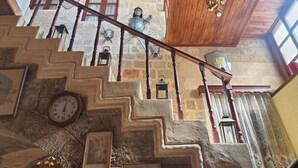A staircase with stone steps, wooden railings, and a view of a stone building with windows and a bell. - Megiston House in Old Town Rhodes (Rodos)