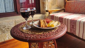 A table with wine glasses, snacks, and a plate of food in a cozy room with a stone wall and a patterned sofa. - Megiston House in Old Town Rhodes (Rodos)