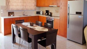 Una cocina moderna con armarios de madera, un refrigerador de acero inoxidable y una mesa de comedor con sillas.
