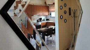 Una cocina con armarios de madera, una mesa de comedor y un perchero.
