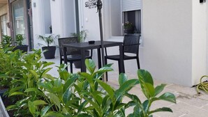 An outdoor patio with a table and chairs, surrounded by potted plants. - Casa d'oro 56 Living in Paradisi Rhodes (Paradisi)