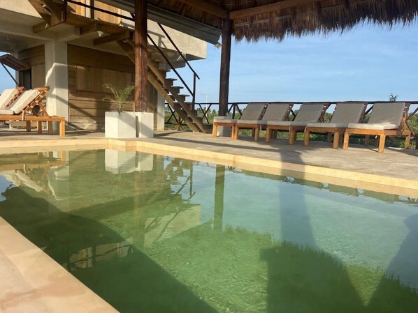 Une piscine dotée de chaises longues et d’un escalier menant à un niveau supérieur.