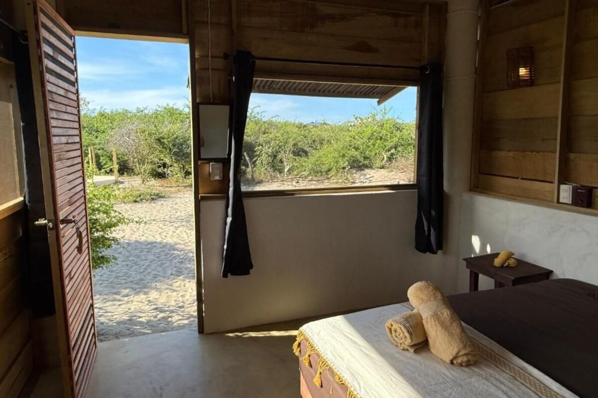 Une chambre avec un lit, une fenêtre avec des rideaux, une petite table et une vue sur l’extérieur.