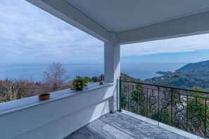 Un balcon avec vue sur la mer et les collines.