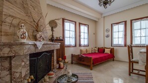 Una sala de estar amplia con chimenea, una cama con cubrecama rojo y un comedor con mesa y sillas de madera.
