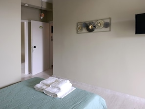 Une chambre à coucher comprenant un lit, une porte, un élément décoratif fixé au mur et un téléviseur.