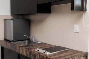 A kitchen with a built-in refrigerator, a sink, and an induction cooktop. - Mojarra: Suite, Design with Kitchenette and Sofa Bed (Cancún)
