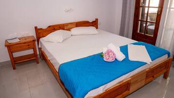 Una cama bien hecha con una colcha azul, almohadas blancas y un arreglo floral.