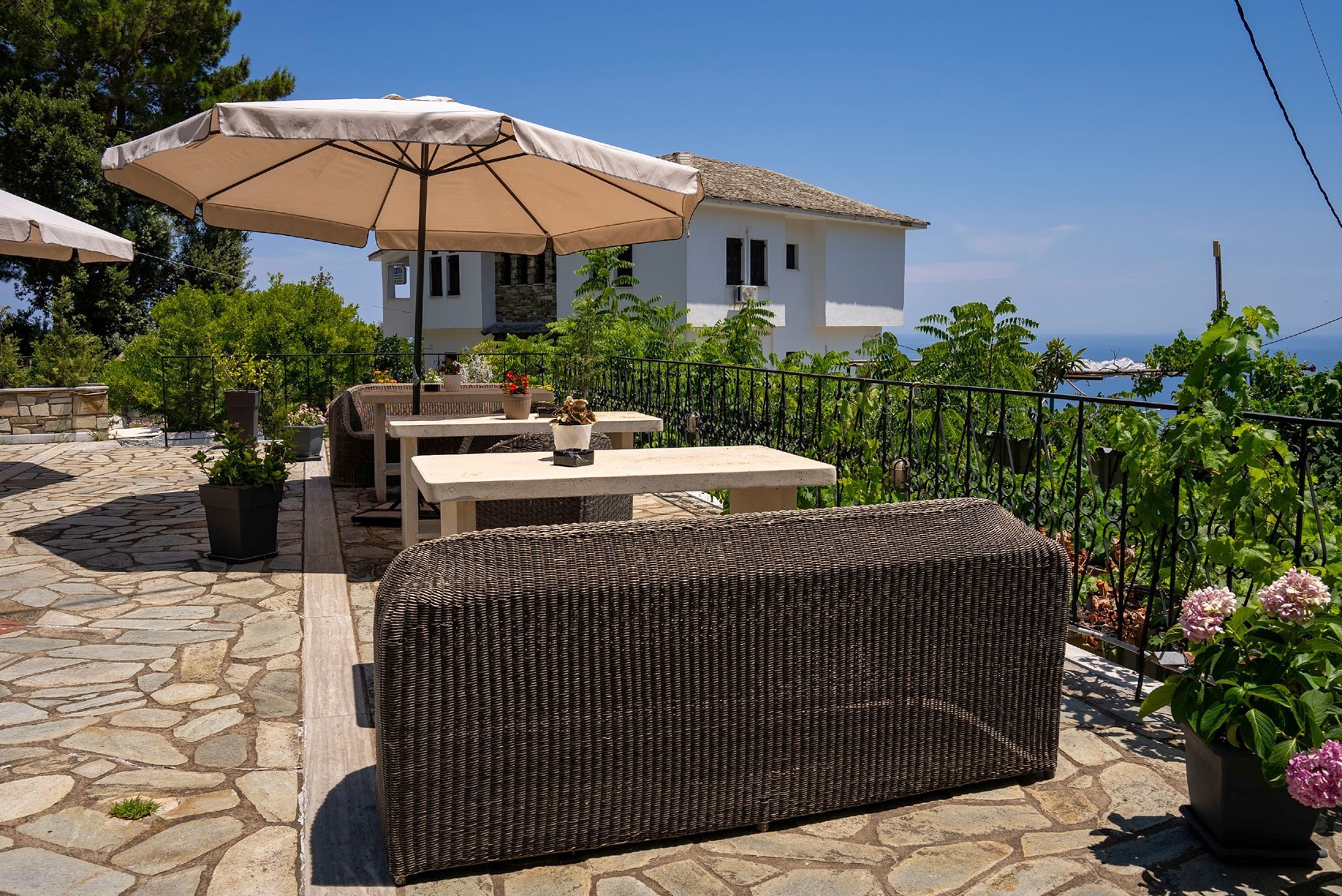 Eine Terrasse im Freien mit Korbmöbeln, einem Tisch und einem großen Sonnenschirm.