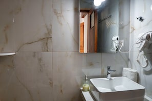Ein Badezimmer mit weißem Waschbecken, einem Spiegel und einer Handbrause.