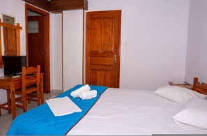 Ein Schlafzimmer mit einem Bett, einem Schreibtisch mit Computer, einem Stuhl und einem Holzschrank.
