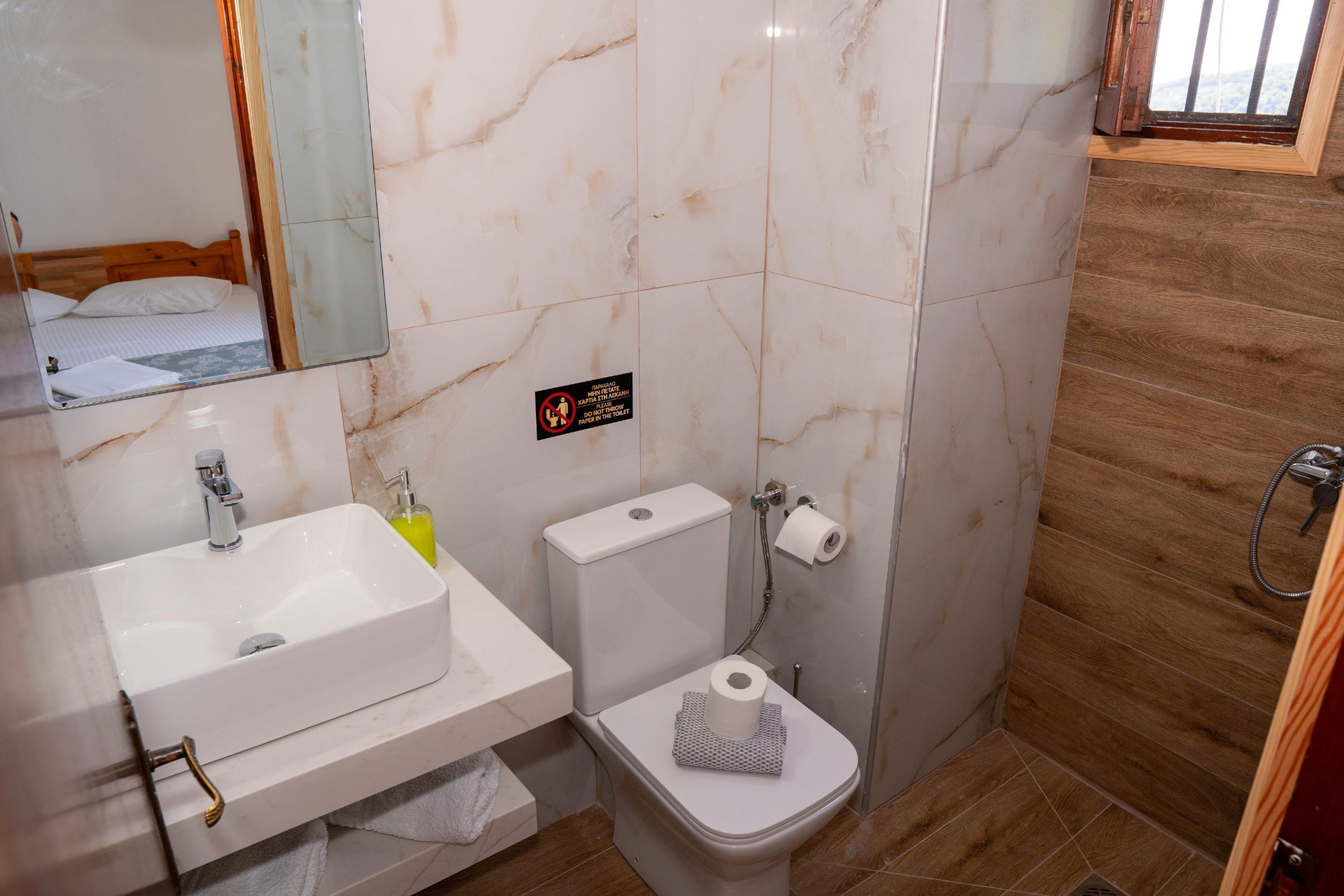 Une salle de bain avec un lavabo, des toilettes et un miroir, le tout de couleur blanche.