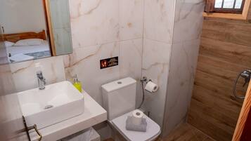 Une salle de bain avec un lavabo, des toilettes et un miroir, le tout de couleur blanche.