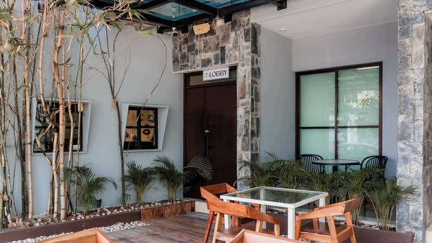 A modern lobby with a stone wall, a glass door, and a sign reading 'Lobby.' There are wooden chairs and a table, and plants are visible. - Mojarra: Suites with Balcony in Cancún Heart (Cancún)