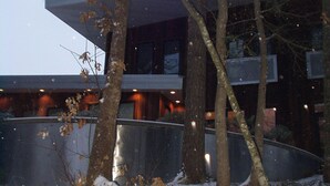 Ein modernes Gebäude mit flachem Dach, umgeben von Bäumen und bedeckt mit Schnee.