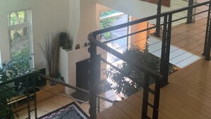 Ein geräumiger Innenraum mit hoher Decke, einer Treppe mit schwarzen Geländern und einem großen abstrakten Gemälde an der Wand.