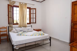 Una camera da letto con un letto, una testata in legno, un comodino, una sedia e una porta in legno.
