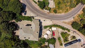 Vista aerea di una zona residenziale caratterizzata da una strada curvilinea, edifici in pietra e vegetazione.