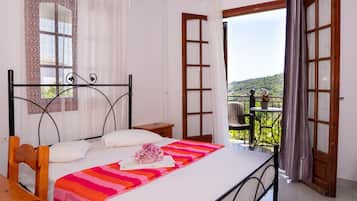 Una camera da letto con un letto, una sedia, un tavolino e un balcone vista campagna.
