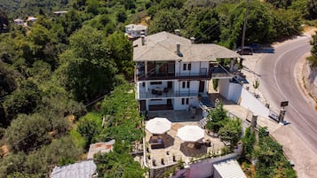 Una casa a due piani con un balcone, un patio in pietra e una strada curva nelle vicinanze.