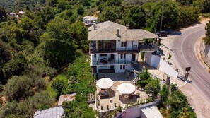 Una casa a due piani con un balcone, un patio in pietra e una strada curva nelle vicinanze.