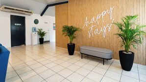 Een modern ingerichte receptie met een houten wand, een bank en potplanten.