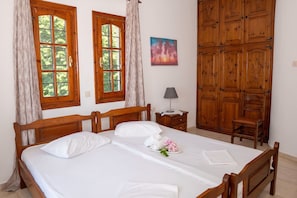 A neatly made bed with white linens, a wooden headboard, and a small table with a lamp beside it. - Paradeisos Αpartment with Sea View (Agios Dimitrios Piliou)