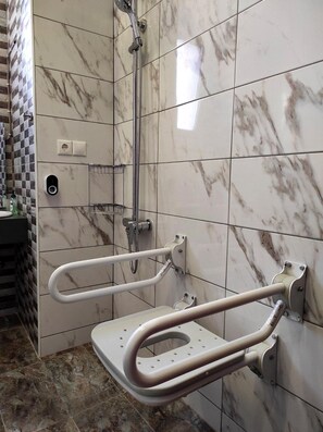 Kylpyhuone, jossa on suihku, tukikaiteet ja wc.