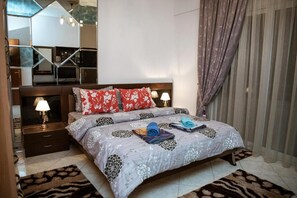 A bedroom with a bed, nightstands, a mirror, and curtains.