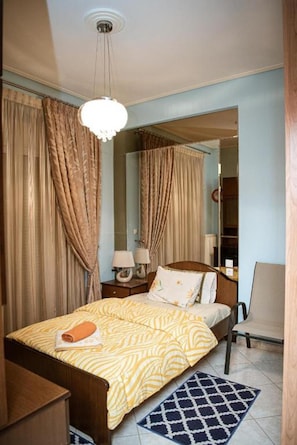 A bedroom with a bed, a nightstand, a lamp, a chair, and a mirror.