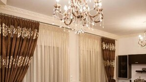 A living room with a brown sofa, a coffee table, and a chandelier. - Vosinakis House in Volos (Volos)