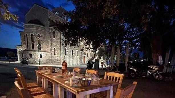 An outdoor dining area with a stone building in the background. - Vosinakis House in Volos (Volos)