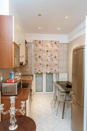 A compact kitchen with a refrigerator, a sink, and a dining area with a table and chairs.