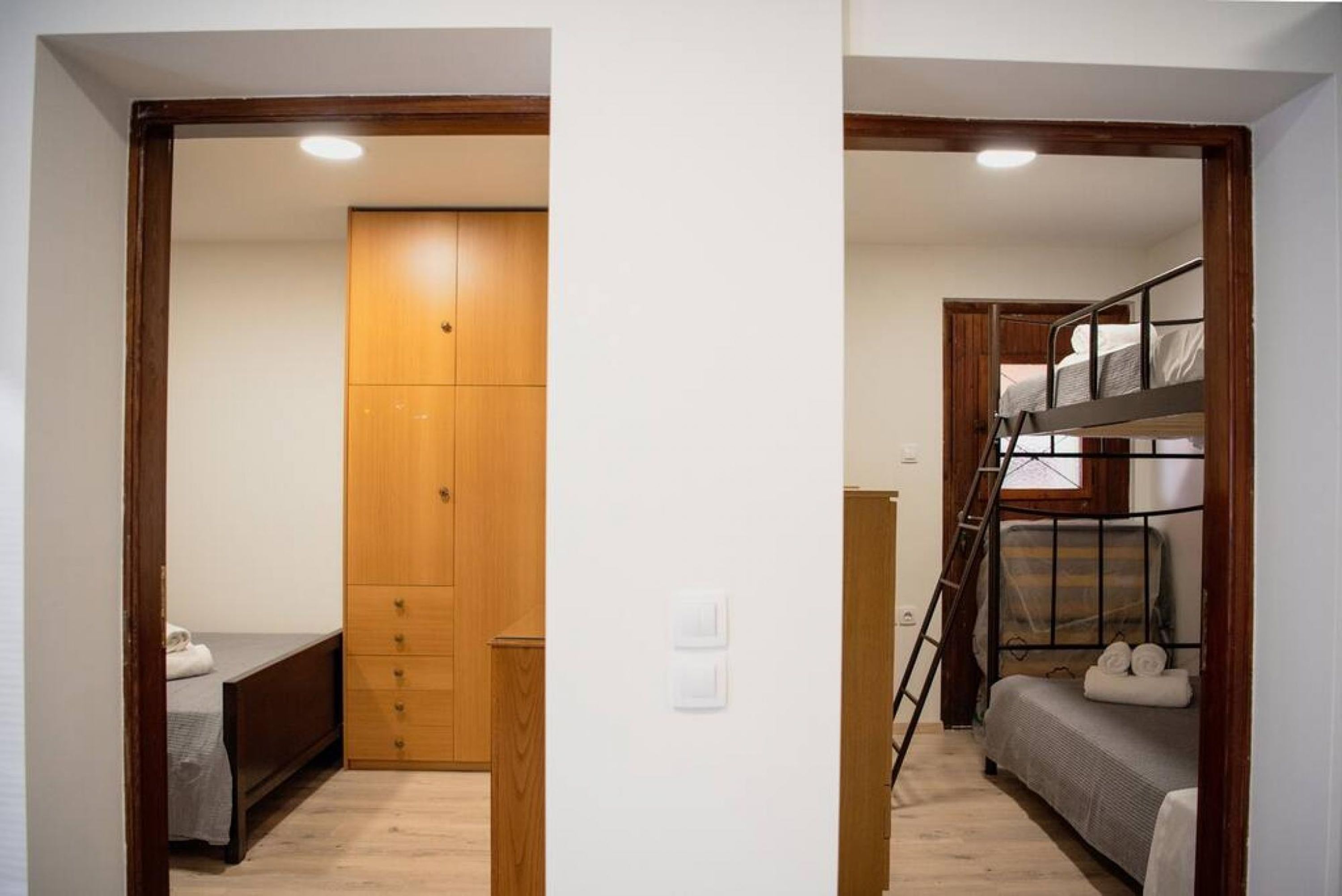 A room with a wooden wardrobe, a bed, and a bunk bed.