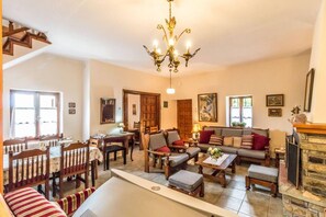 A spacious living room with a fireplace, a dining area with wooden furniture, and a staircase leading to another level.