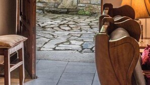 A room with a stone wall, a wooden door, a wooden chair, and a lamp.