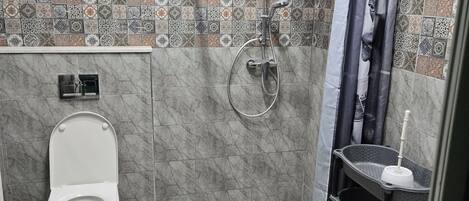 A bathroom with a toilet, shower, and sink.