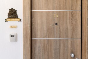 Eine Holztür mit der Nummer 14, einer Messing-Schiffsdekoration, einem Lichtschalter und einem Sicherheitstastenfeld.