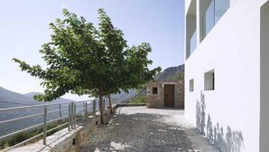 A stone-paved pathway leading to a building with a wooden door, overlooking a mountainous landscape. - Villa Aires with Private Pool (Vrachasi)