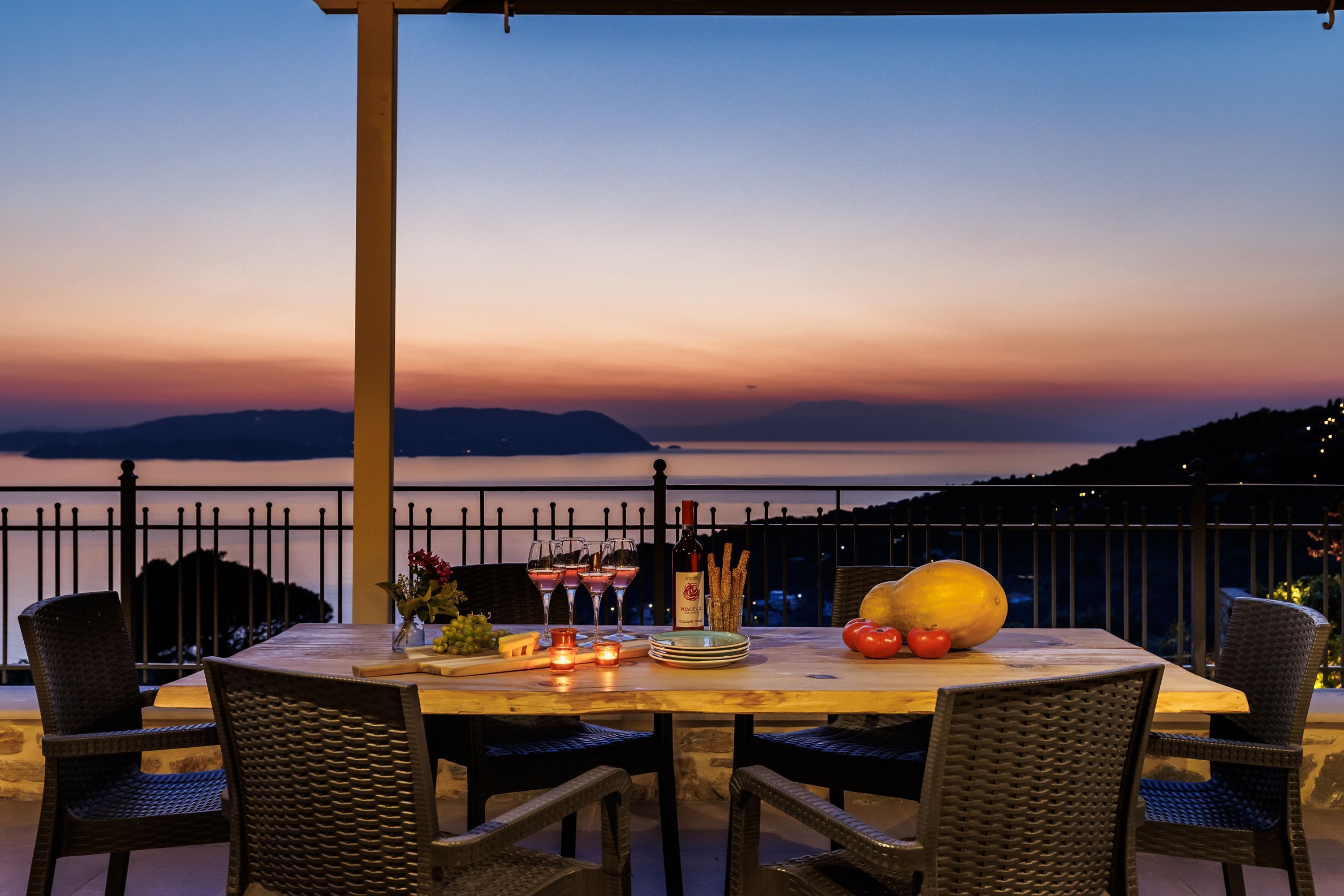 Mesa preparada para comer con vista al mar y montañas al fondo.