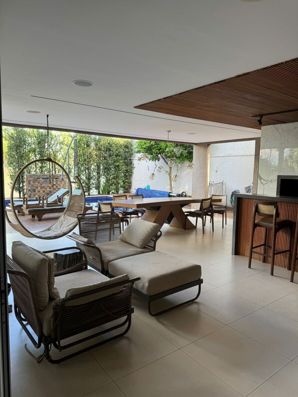 A modern outdoor seating area with lounge chairs, a dining table, and a bar.