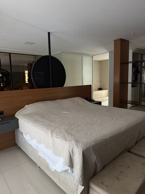 A modern bedroom with a large bed, a bedside table, a mirror, and a wardrobe.